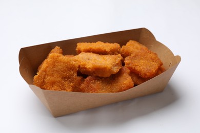 Photo of Delicious chicken nuggets in carton box on white background