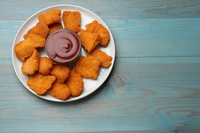 Photo of Delicious chicken nuggets with ketchup on blue wooden table, top view. Space for text