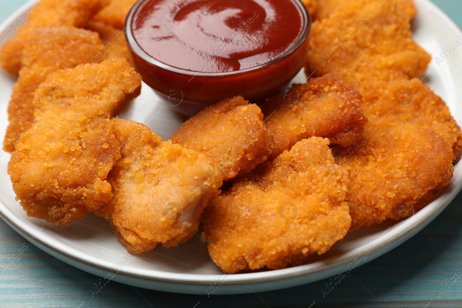 Photo of Delicious chicken nuggets with ketchup on blue table, closeup