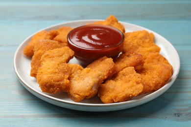 Photo of Delicious chicken nuggets with ketchup on blue wooden table, closeup