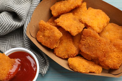 Photo of Delicious chicken nuggets with ketchup on blue wooden table, flat lay