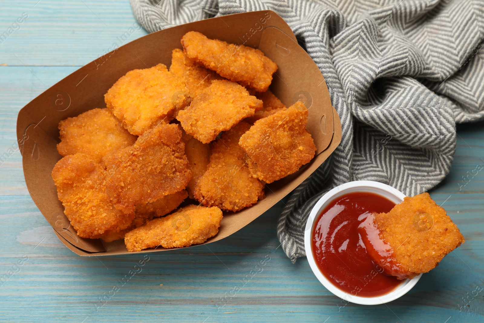 Photo of Delicious chicken nuggets with ketchup on blue wooden table, flat lay