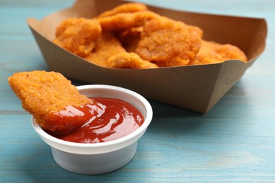 Photo of Delicious chicken nuggets with ketchup on blue wooden table, closeup