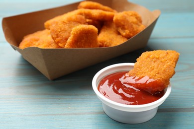 Photo of Delicious chicken nuggets with ketchup on blue wooden table, closeup