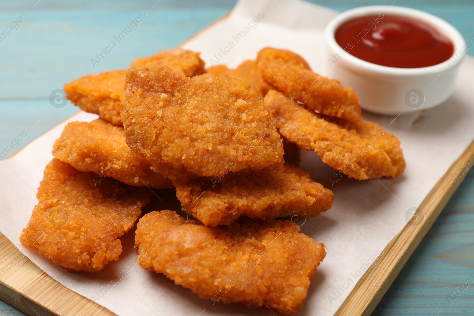 Photo of Delicious chicken nuggets with ketchup on blue wooden table, closeup