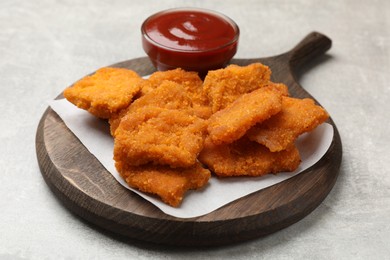 Photo of Delicious chicken nuggets with ketchup on grey textured table, closeup