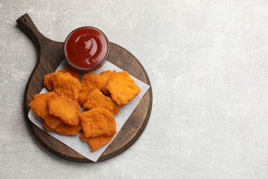 Photo of Delicious chicken nuggets with ketchup on grey textured table, top view. Space for text