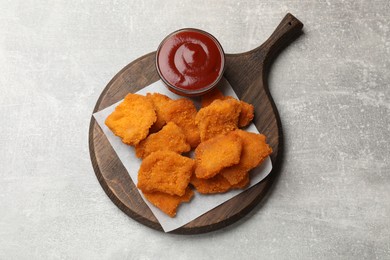 Delicious chicken nuggets with ketchup on grey textured table, top view