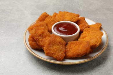 Photo of Delicious chicken nuggets with ketchup on grey textured table, closeup