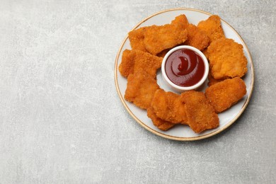 Photo of Delicious chicken nuggets with ketchup on grey textured table, top view. Space for text