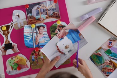 Creating vision board. Girl cutting out picture at light table, closeup