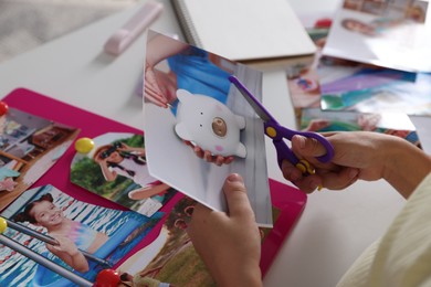 Photo of Creating vision board. Girl cutting out picture at light table, closeup