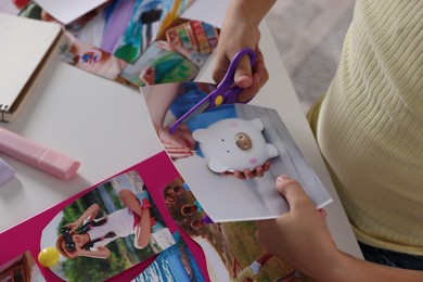 Creating vision board. Girl cutting out picture at light table, closeup