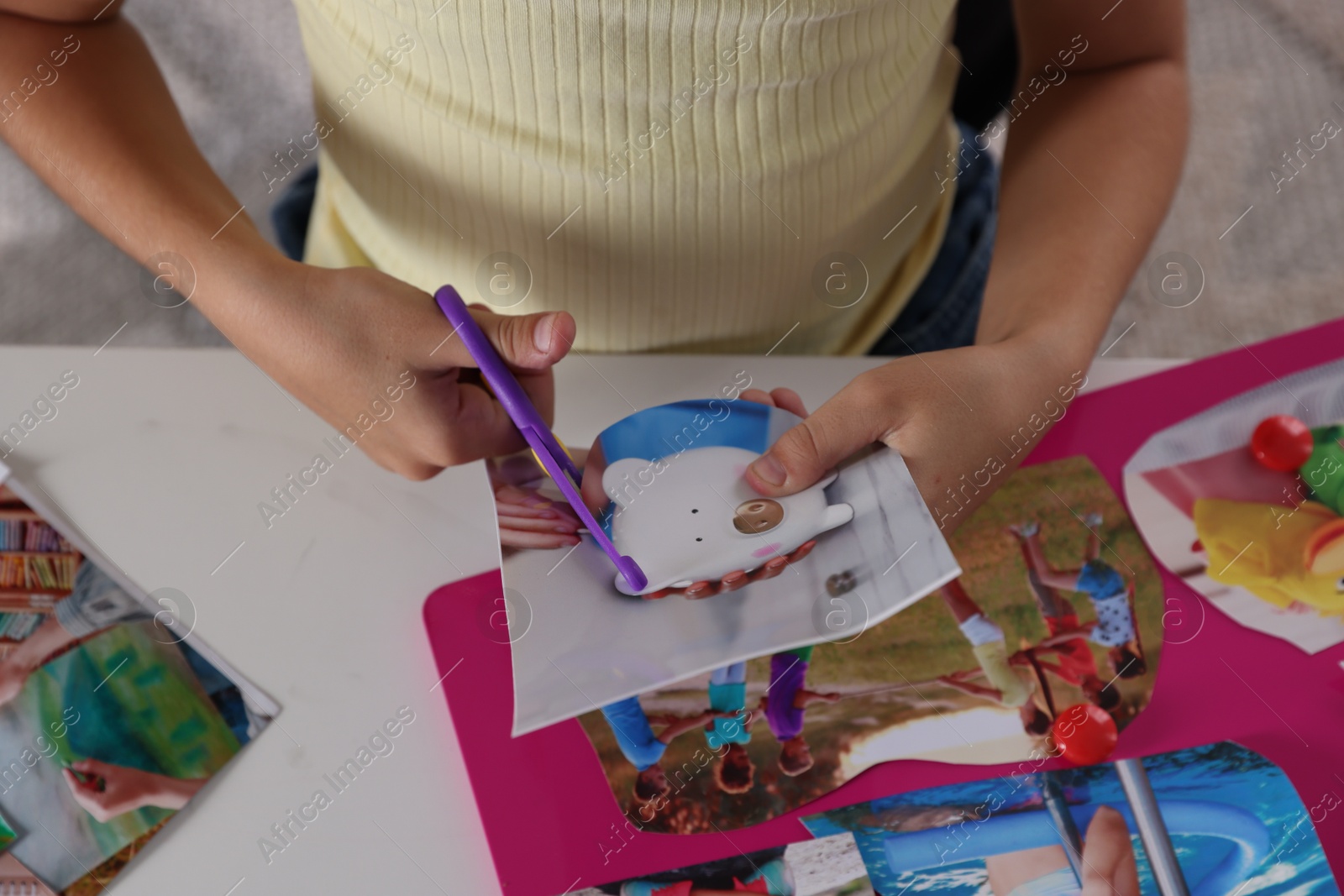 Photo of Creating vision board. Girl cutting out picture at light table, closeup