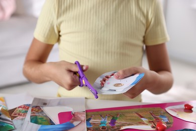 Photo of Creating vision board. Girl cutting out picture at light table, closeup