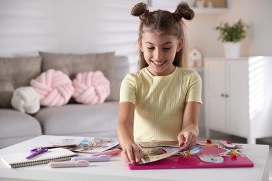 Girl creating vision board with different pictures at light table indoors