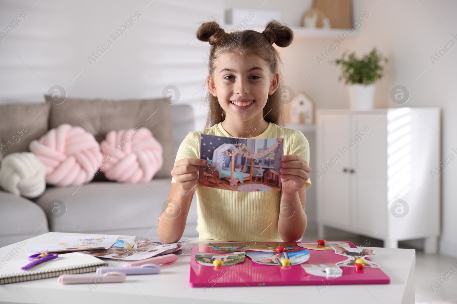 Photo of Creating vision board. Girl with picture at light table indoors