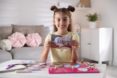 Photo of Creating vision board. Girl with picture at light table indoors