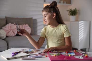 Photo of Girl creating vision board with different pictures at light table indoors