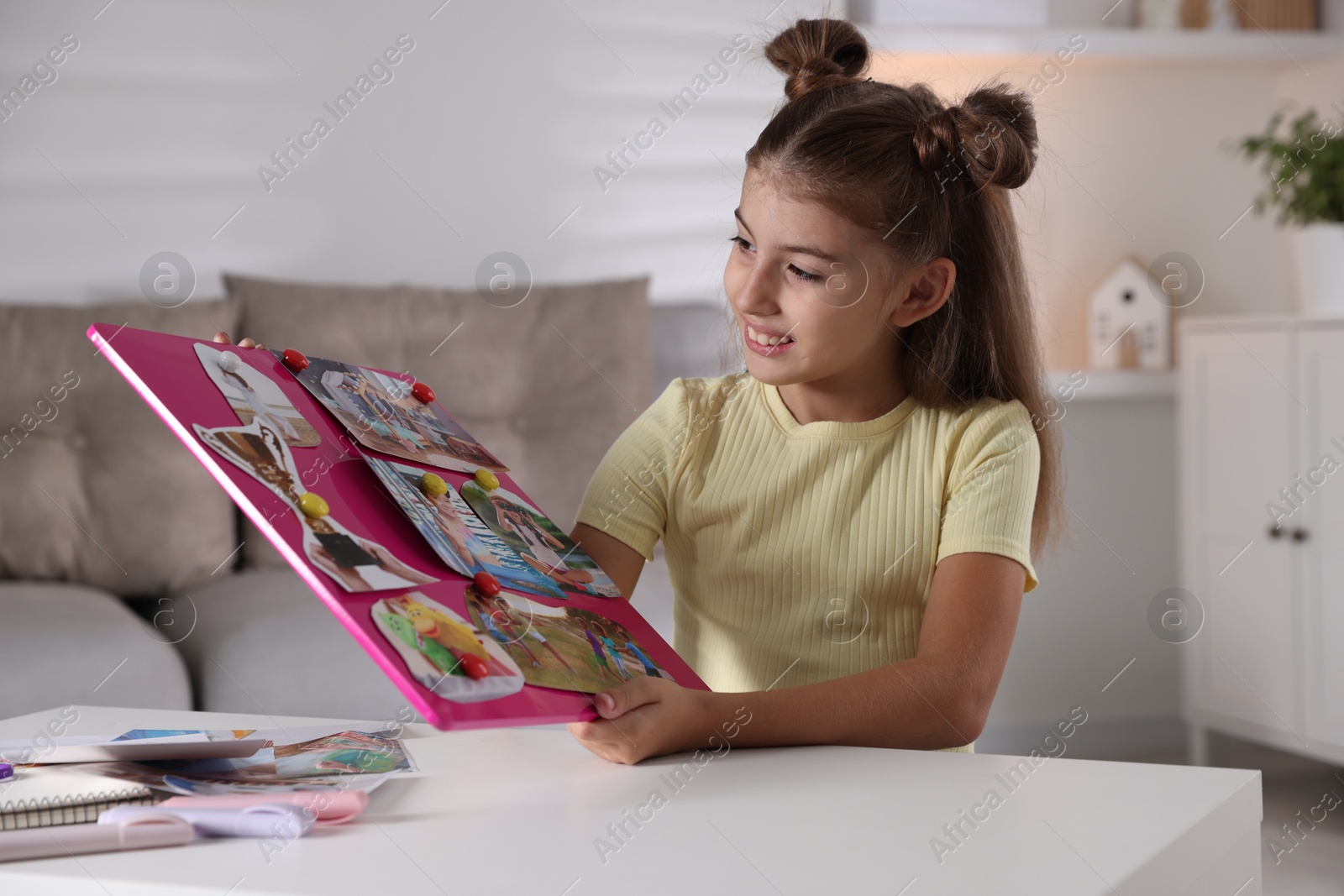 Photo of Girl holding vision board with different pictures at light table indoors