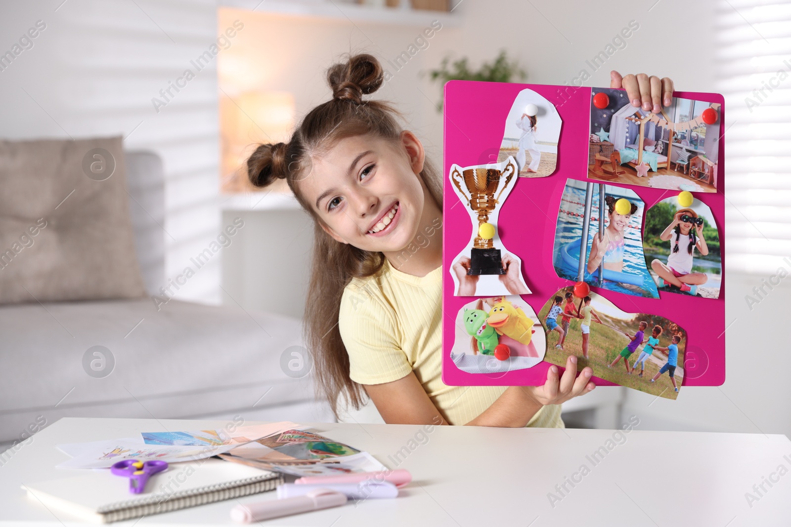 Photo of Girl holding vision board with different pictures at light table indoors