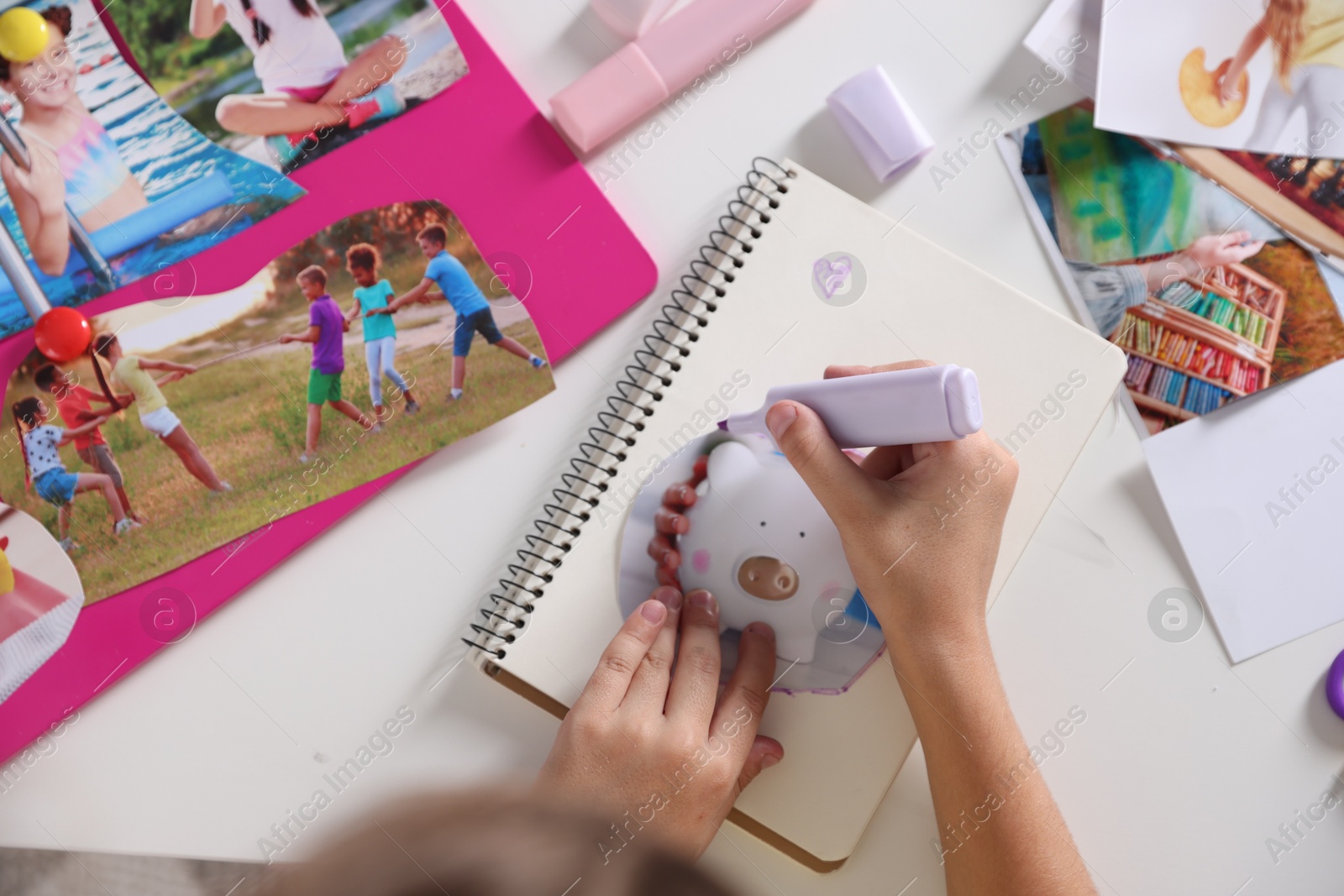 Photo of Creating vision board. Girl outlining picture with violet marker at light table, top view