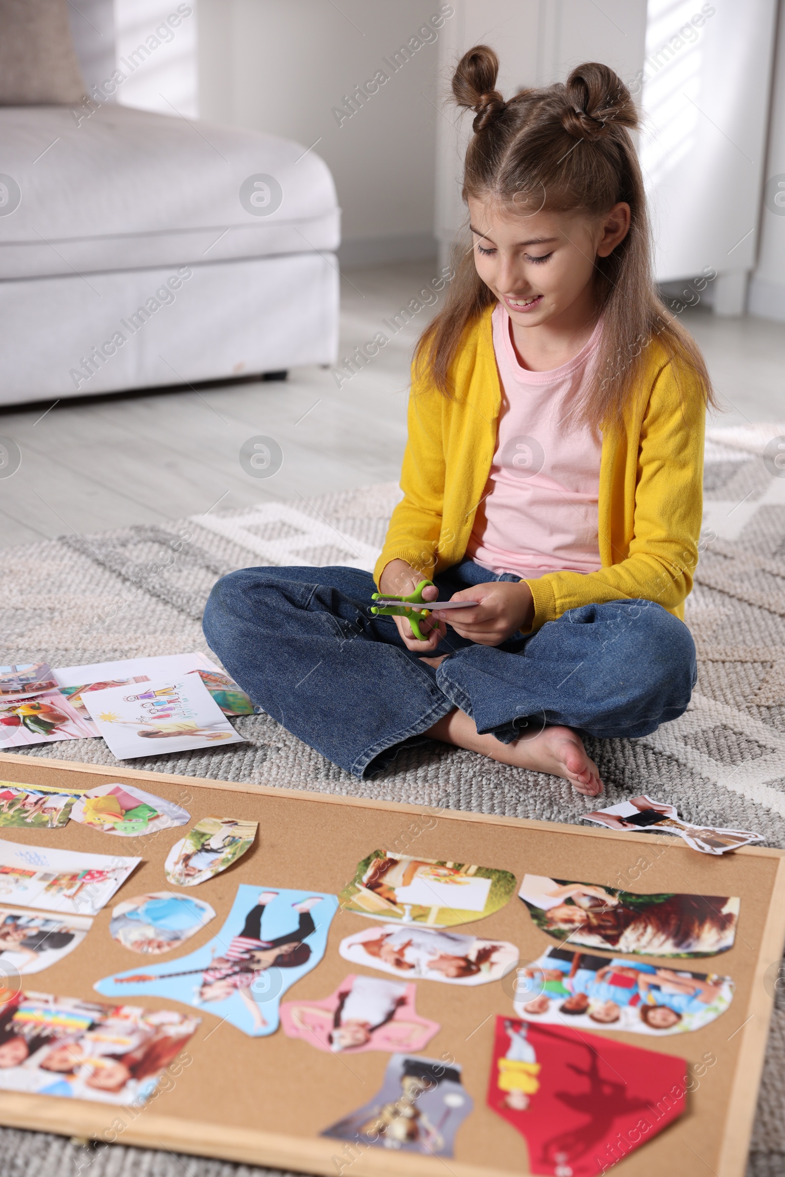 Photo of Creating vision board. Girl cutting out picture on floor indoors