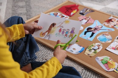 Creating vision board. Girl cutting out picture on floor, closeup