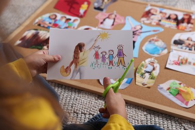 Creating vision board. Girl cutting out picture on floor, closeup