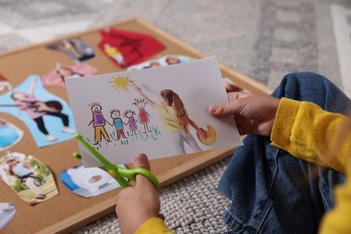 Photo of Creating vision board. Girl cutting out picture on floor, closeup