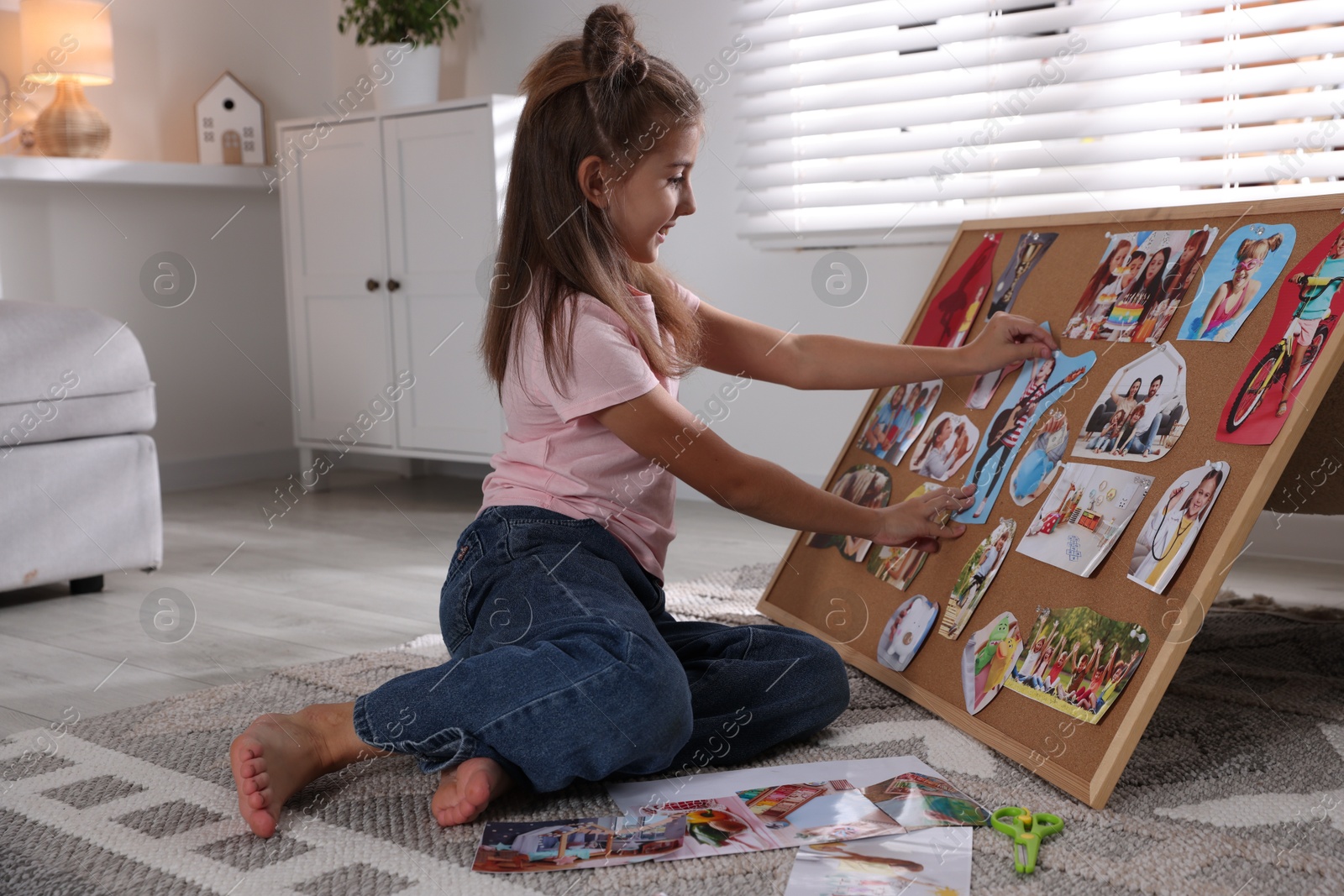 Photo of Girl creating vision board with different pictures on floor indoors