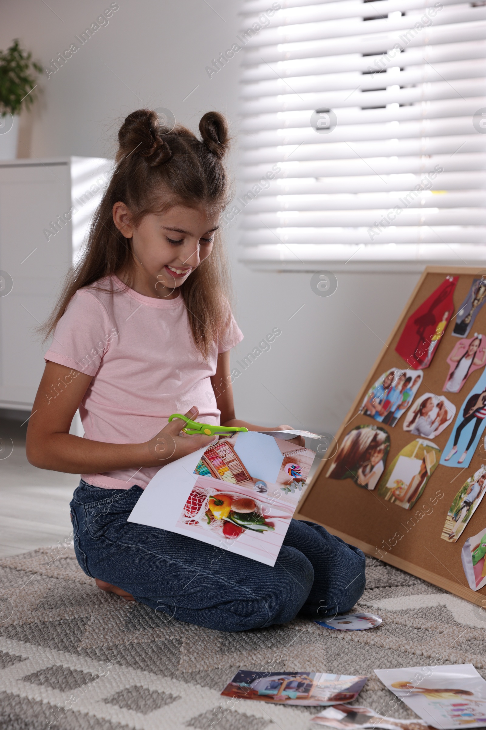 Photo of Creating vision board. Girl cutting out picture on floor indoors