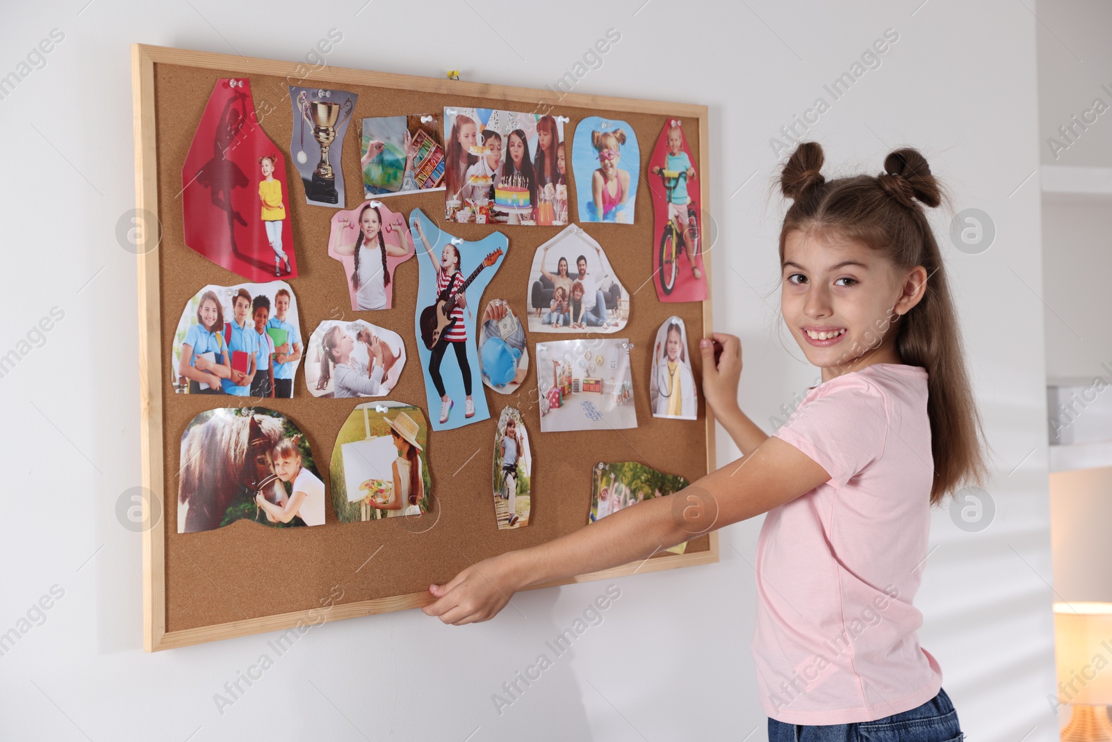 Photo of Girl hanging vision board with different pictures on wall indoors