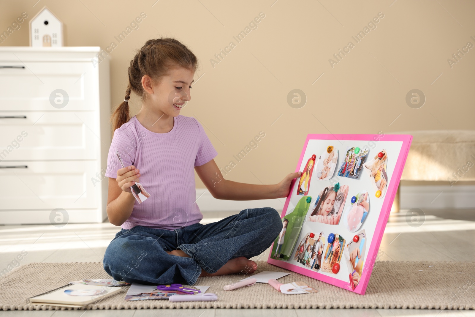 Photo of Girl creating vision board with different pictures on floor indoors