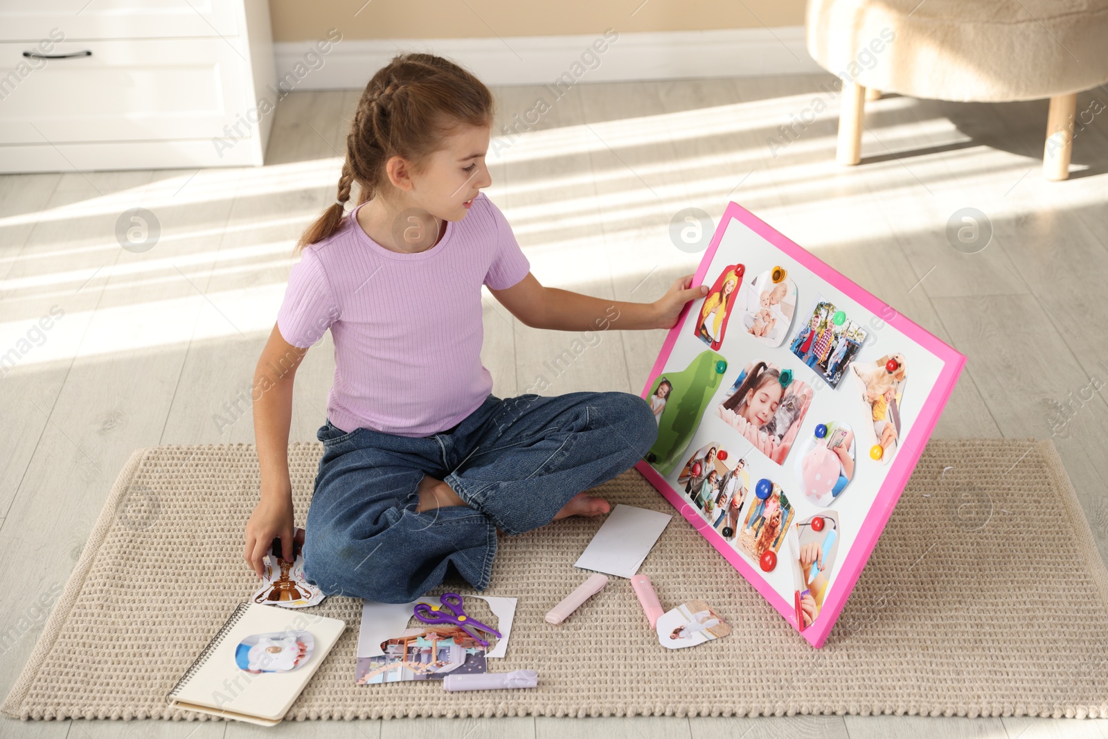 Photo of Girl creating vision board with different pictures on floor indoors