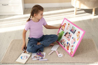 Girl creating vision board with different pictures on floor indoors