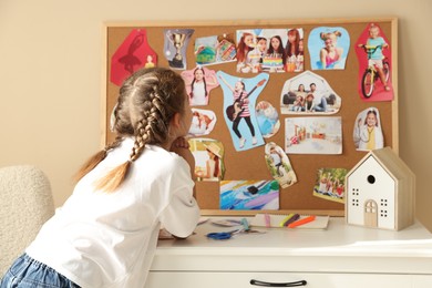 Girl creating looking at vision board with different pictures indoors