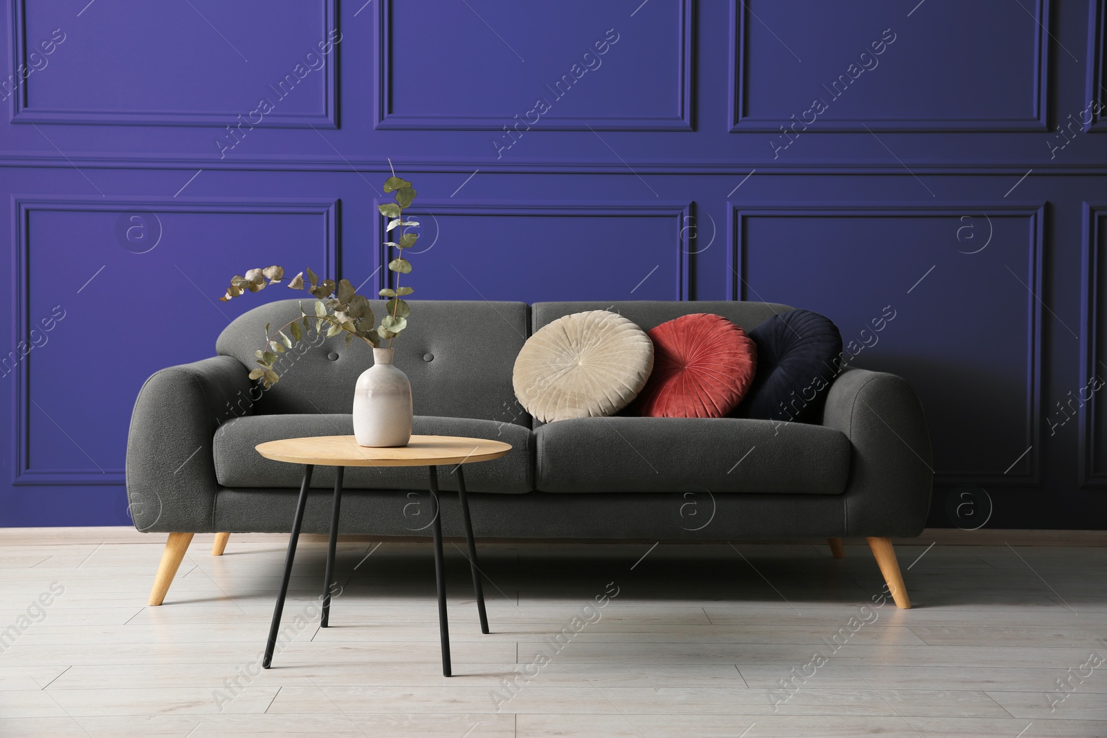 Image of Grey sofa with cushions and table near indigo color wall in room