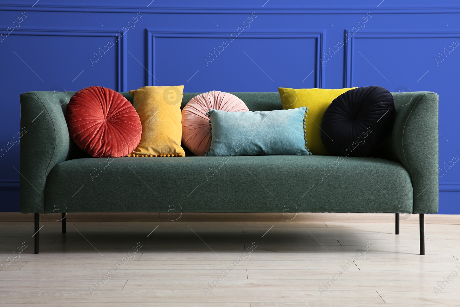 Image of Comfortable sofa with cushions near blue wall in room