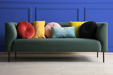 Image of Comfortable sofa with cushions near blue wall in room