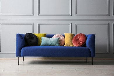 Image of Blue sofa with cushions near grey color wall in room