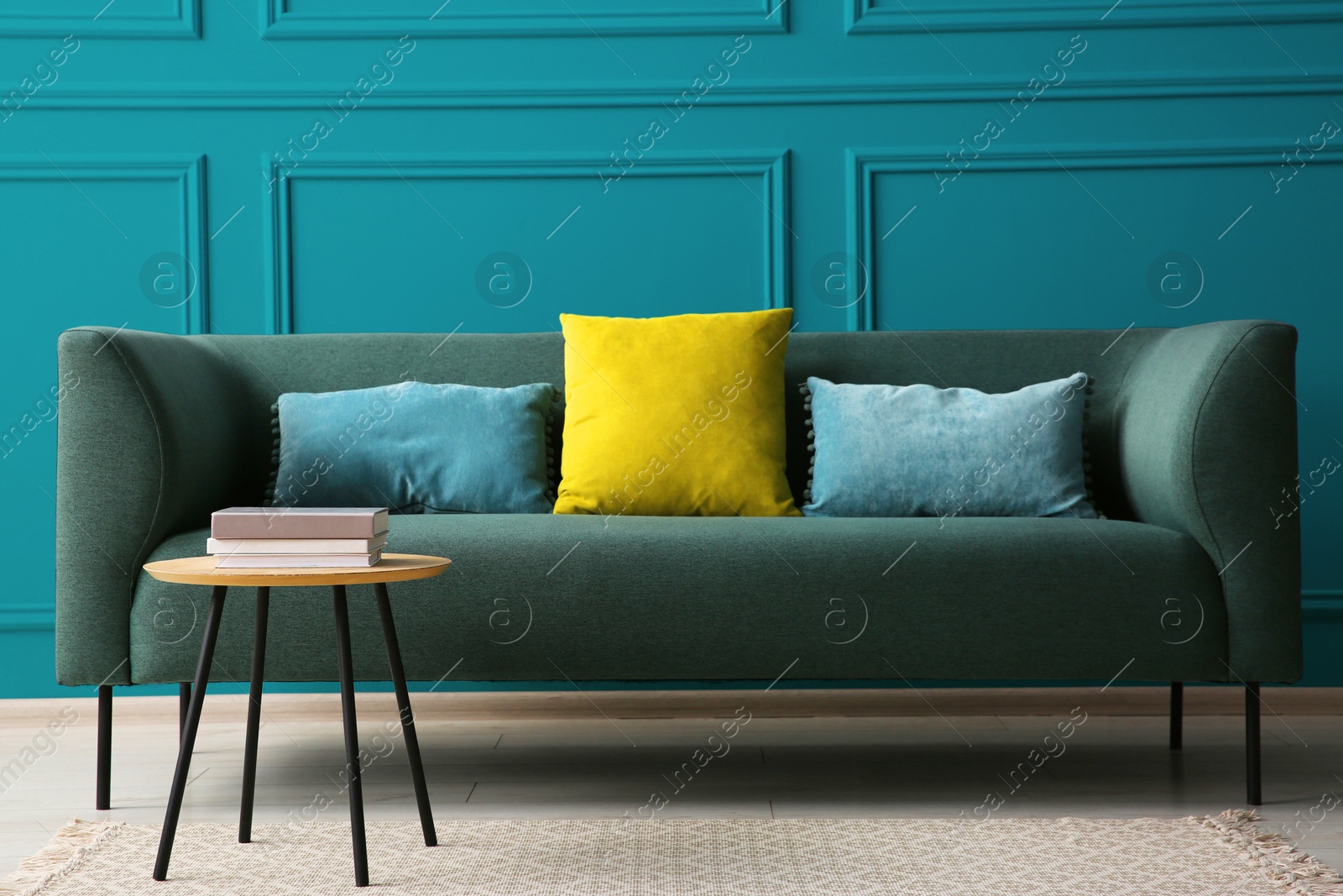 Image of Comfortable sofa and table near teal color wall in room