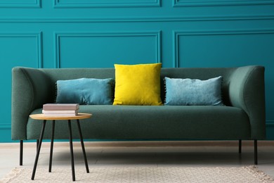 Image of Comfortable sofa and table near teal color wall in room