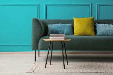 Image of Comfortable sofa and table near teal color wall in room