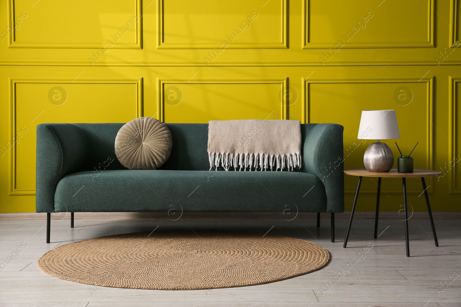 Image of Comfortable sofa and table near golden color wall in room