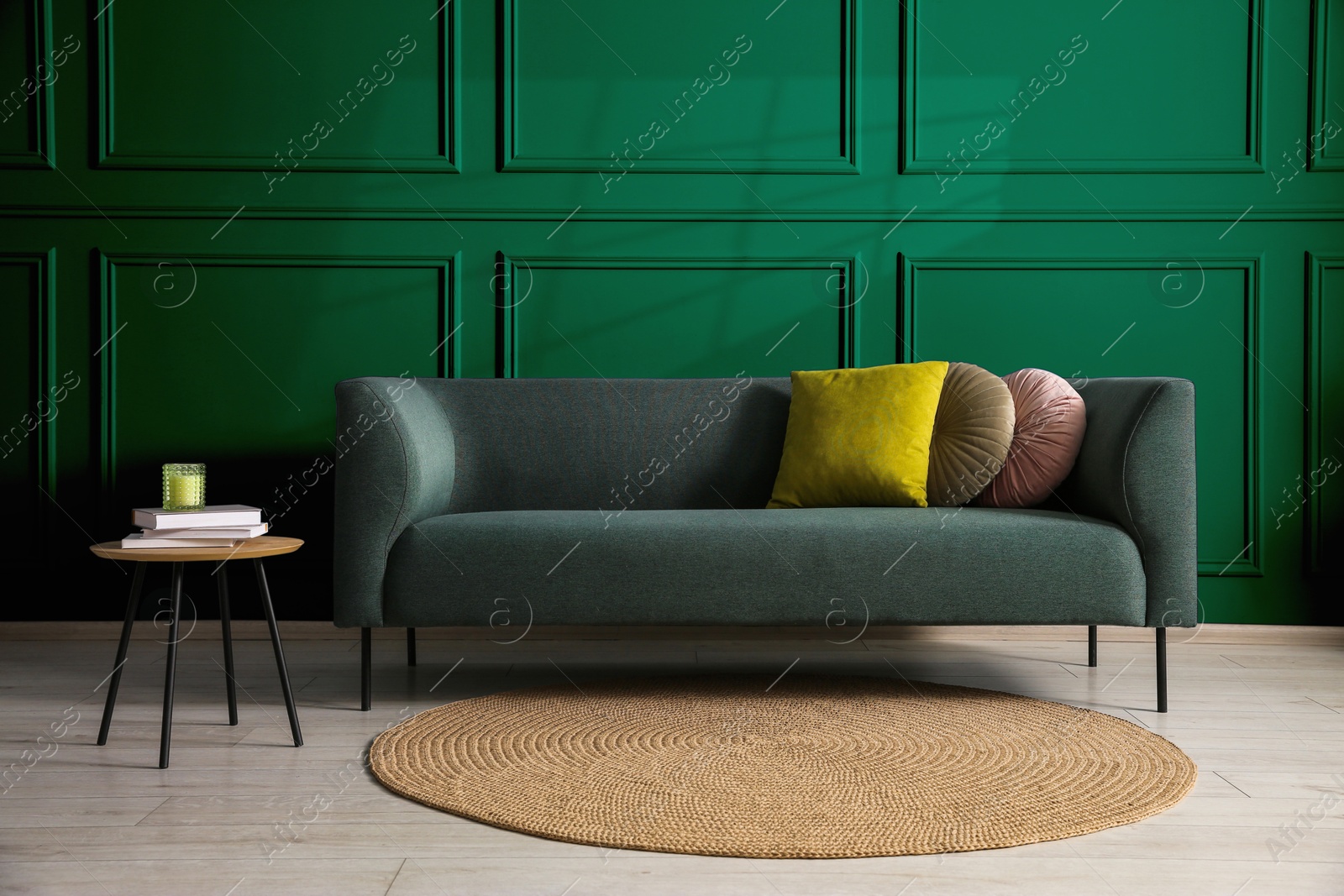 Image of Comfortable sofa with cushions and table near green wall in room