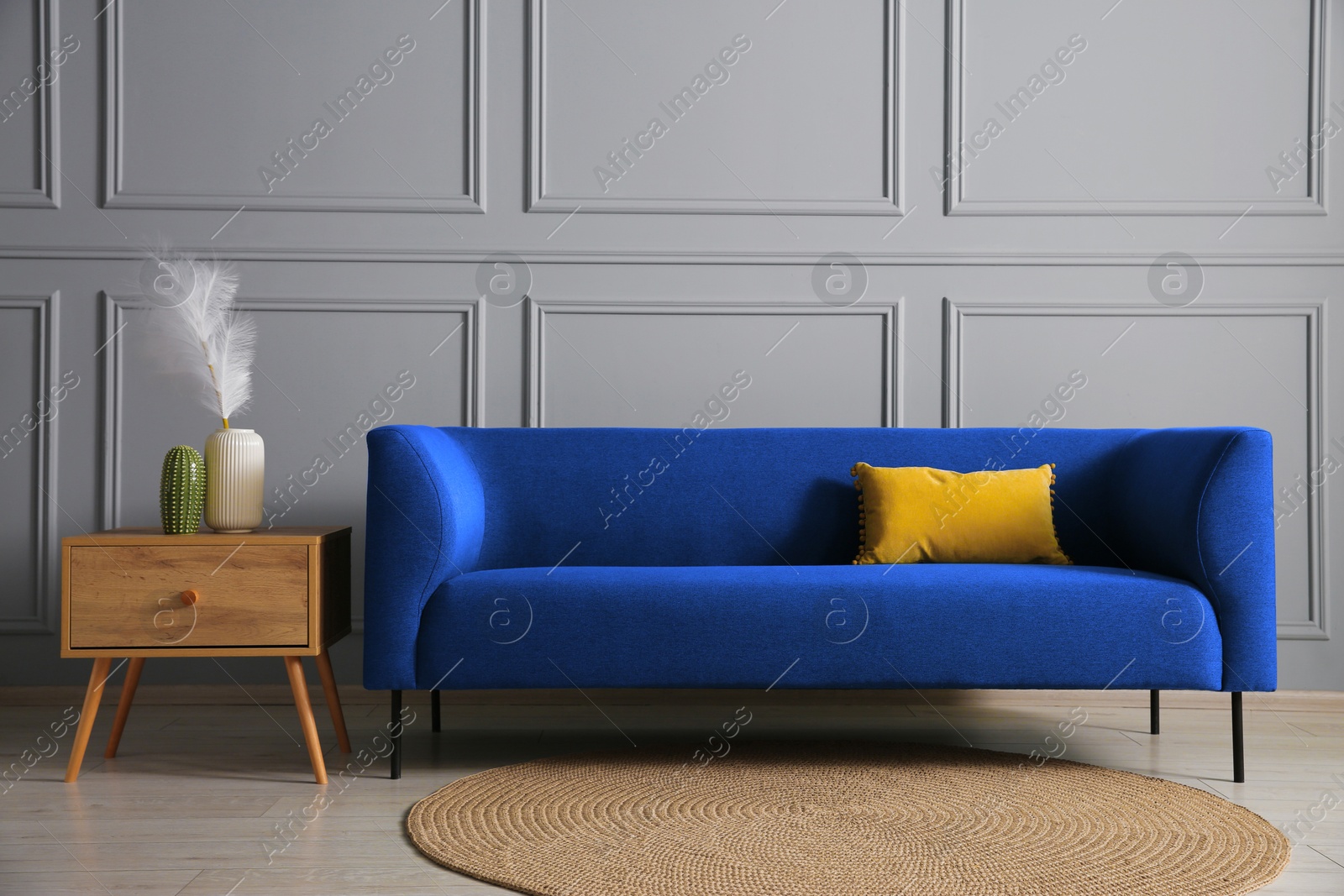 Image of Blue sofa and side table near grey wall in room