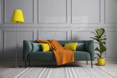 Image of Comfortable sofa, floor lamp and houseplant near light grey wall in room