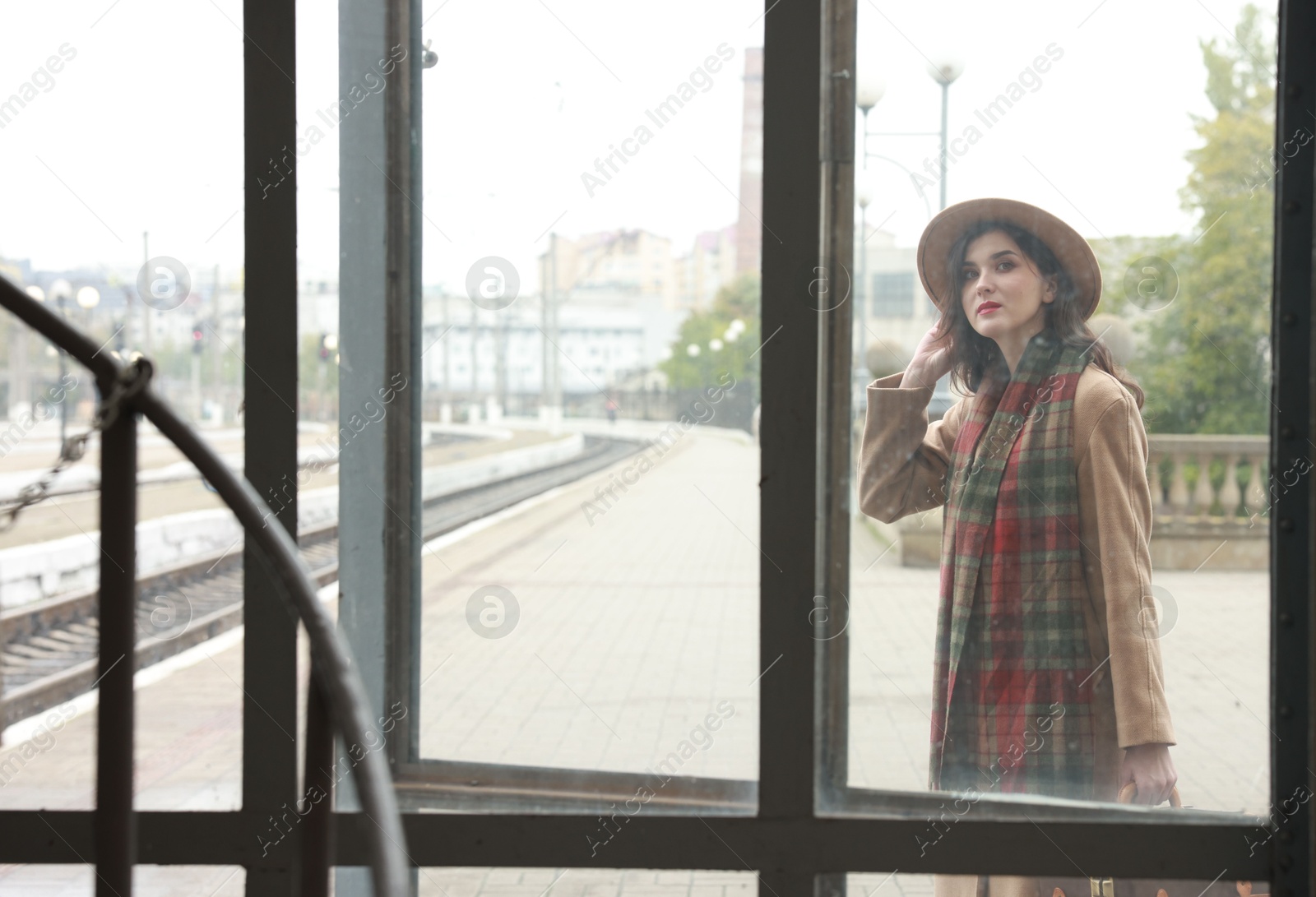 Photo of Woman with at railway station, view through glass window