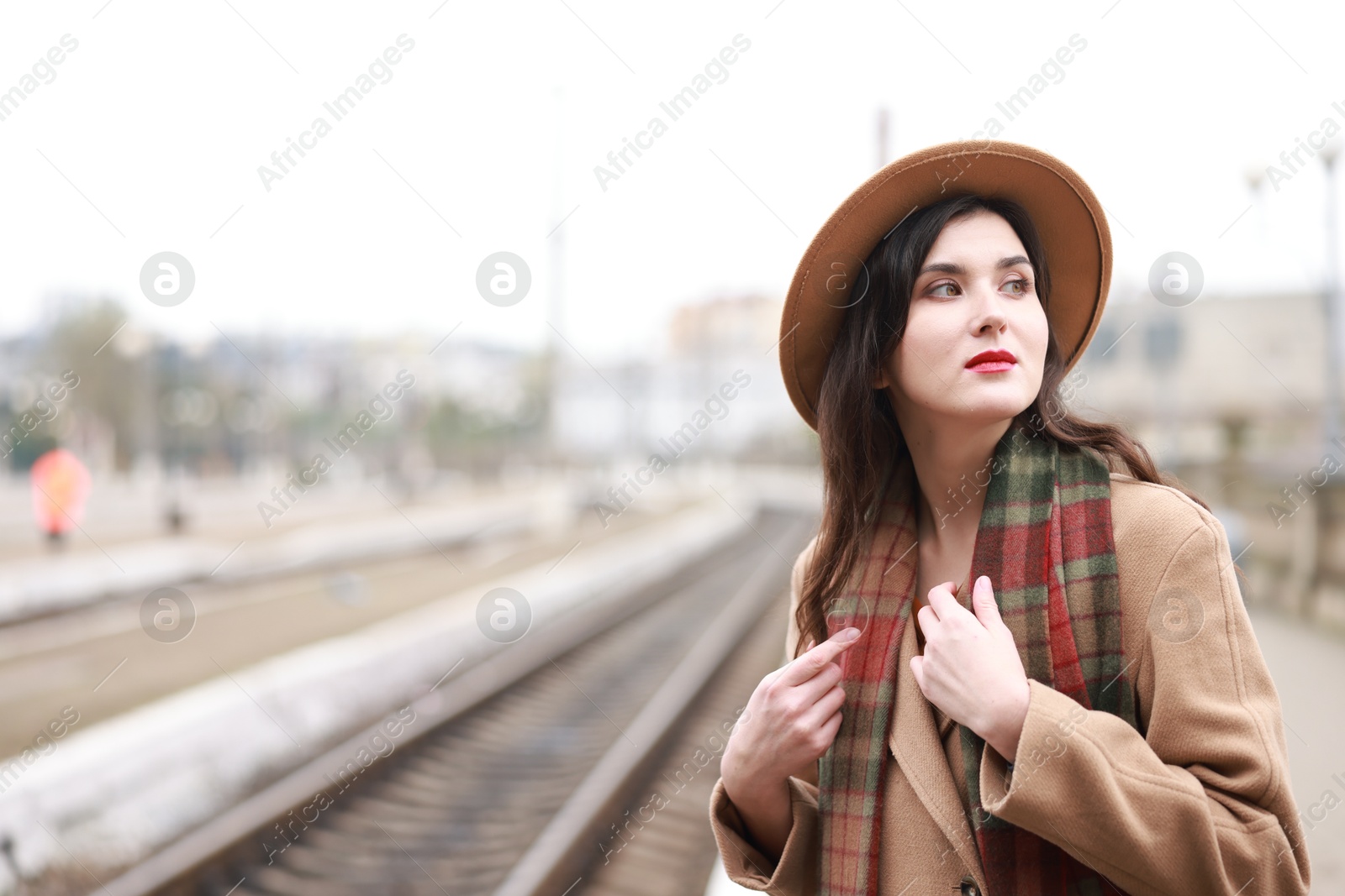 Photo of Beautiful woman in hat at railway station, space for text